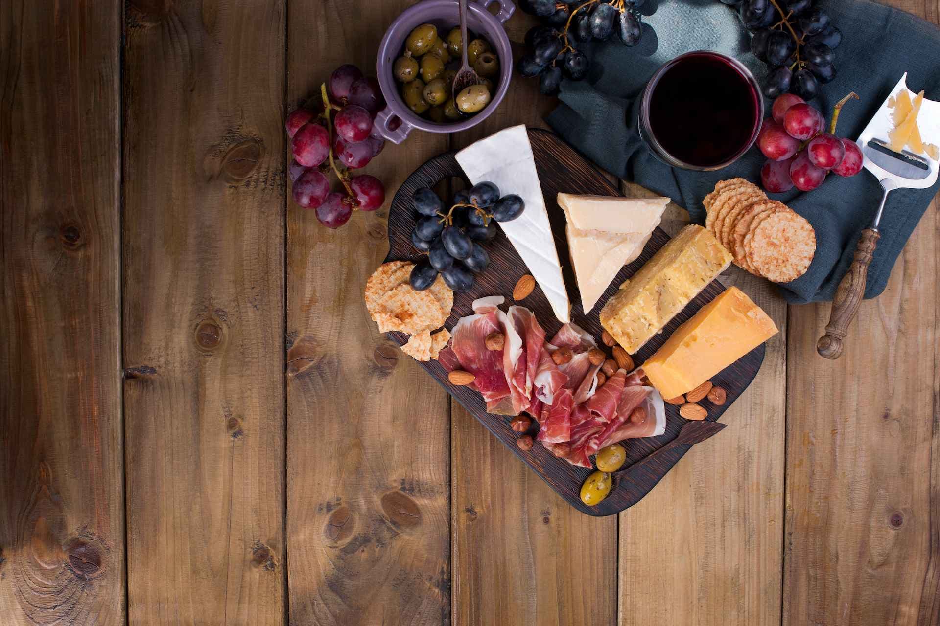 Tabla de madera con quesos, embutidos y frutas para acompañar vino y cócteles